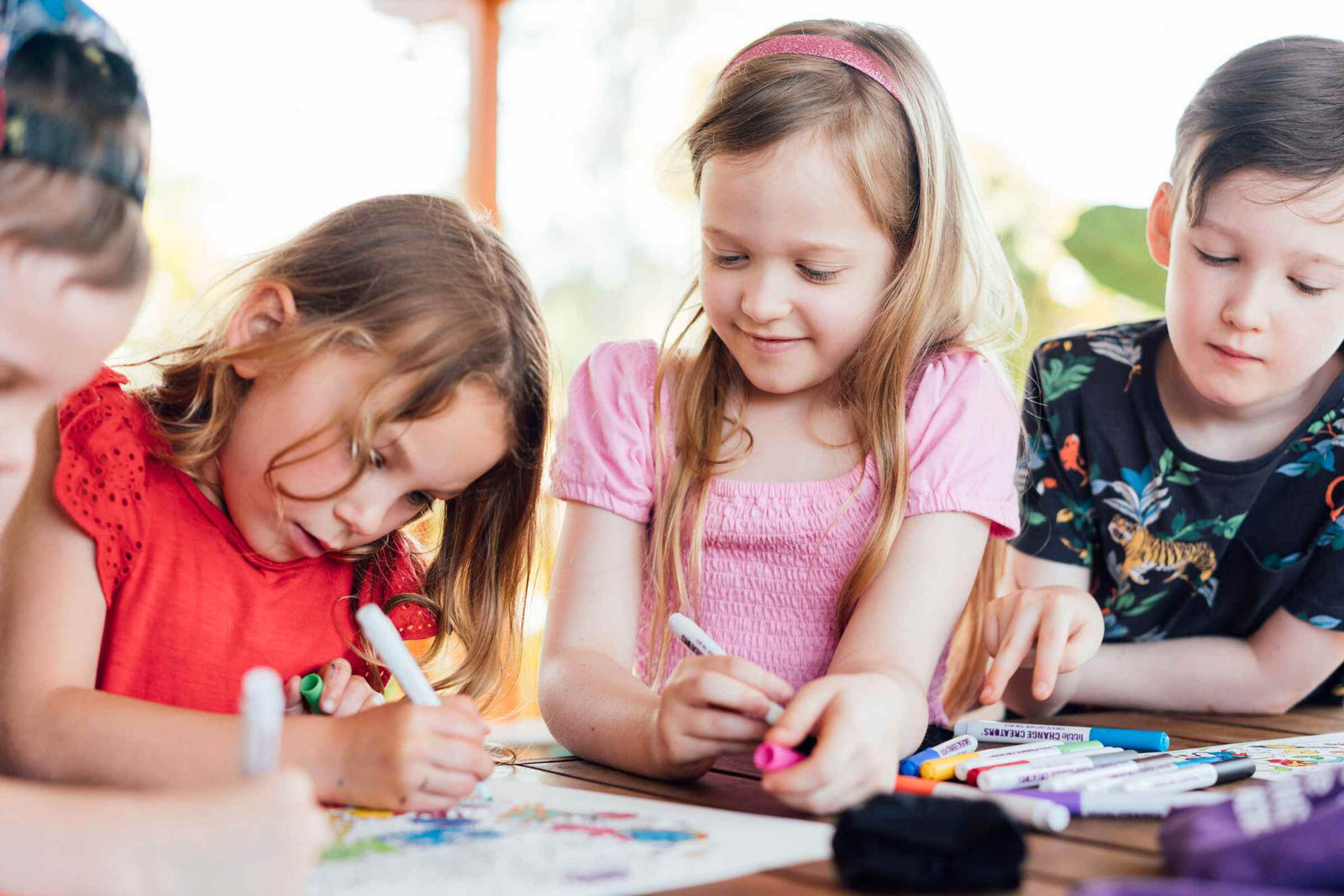 Four children gathered around a table and having fun colouring on a silicone mat.
