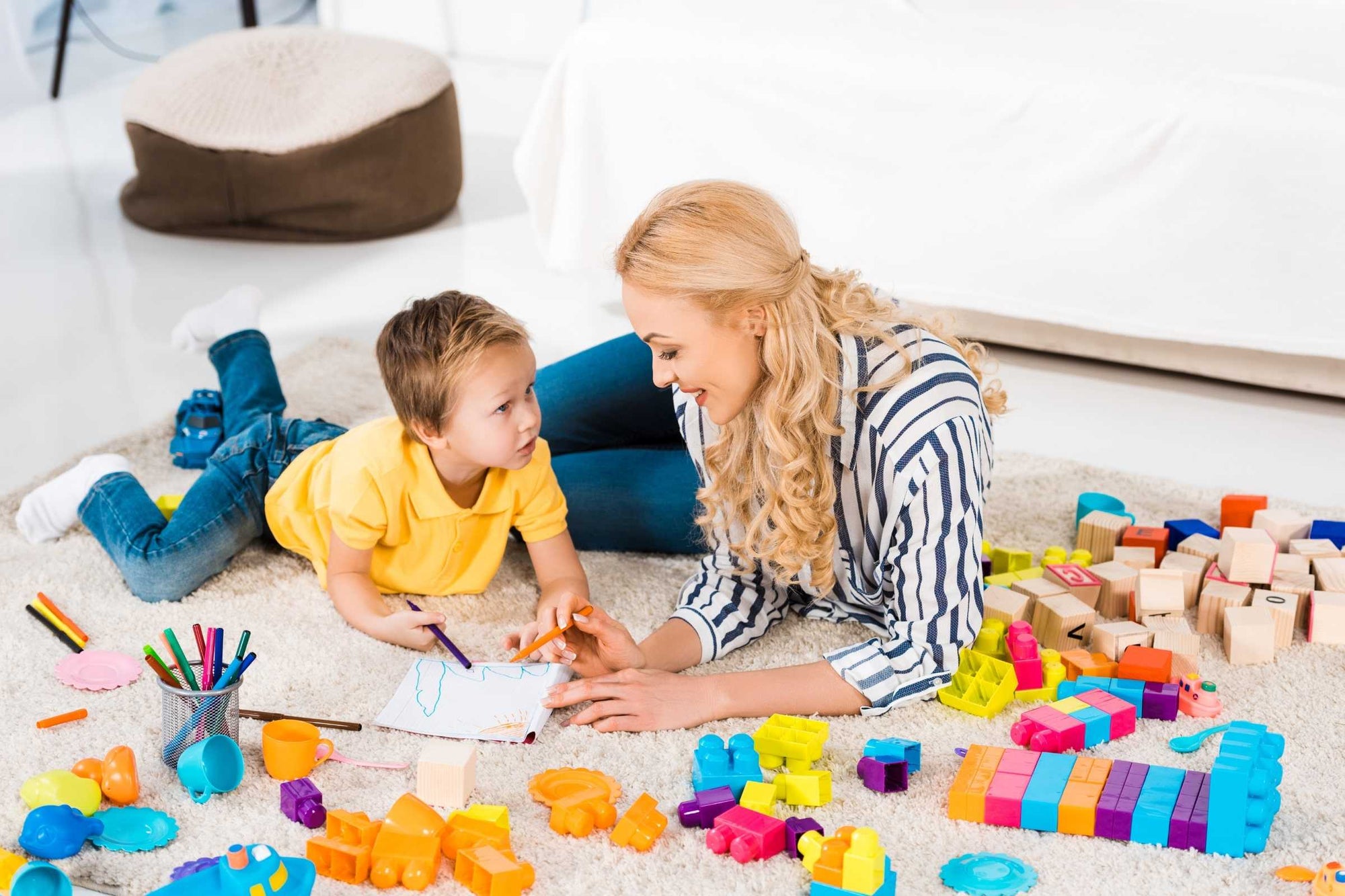 A mother sparks her child's curiosity with educational toys including building blocks and colouring mats