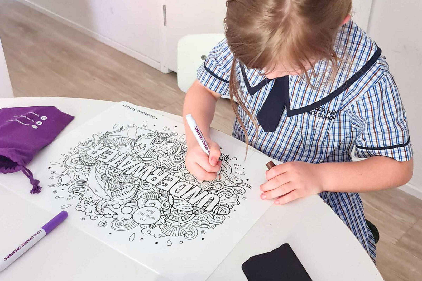 Young child practising fine motor skills by colouring on a reusable silicone colouring mat at a table, supporting school readiness through calm, screen-free creative play.