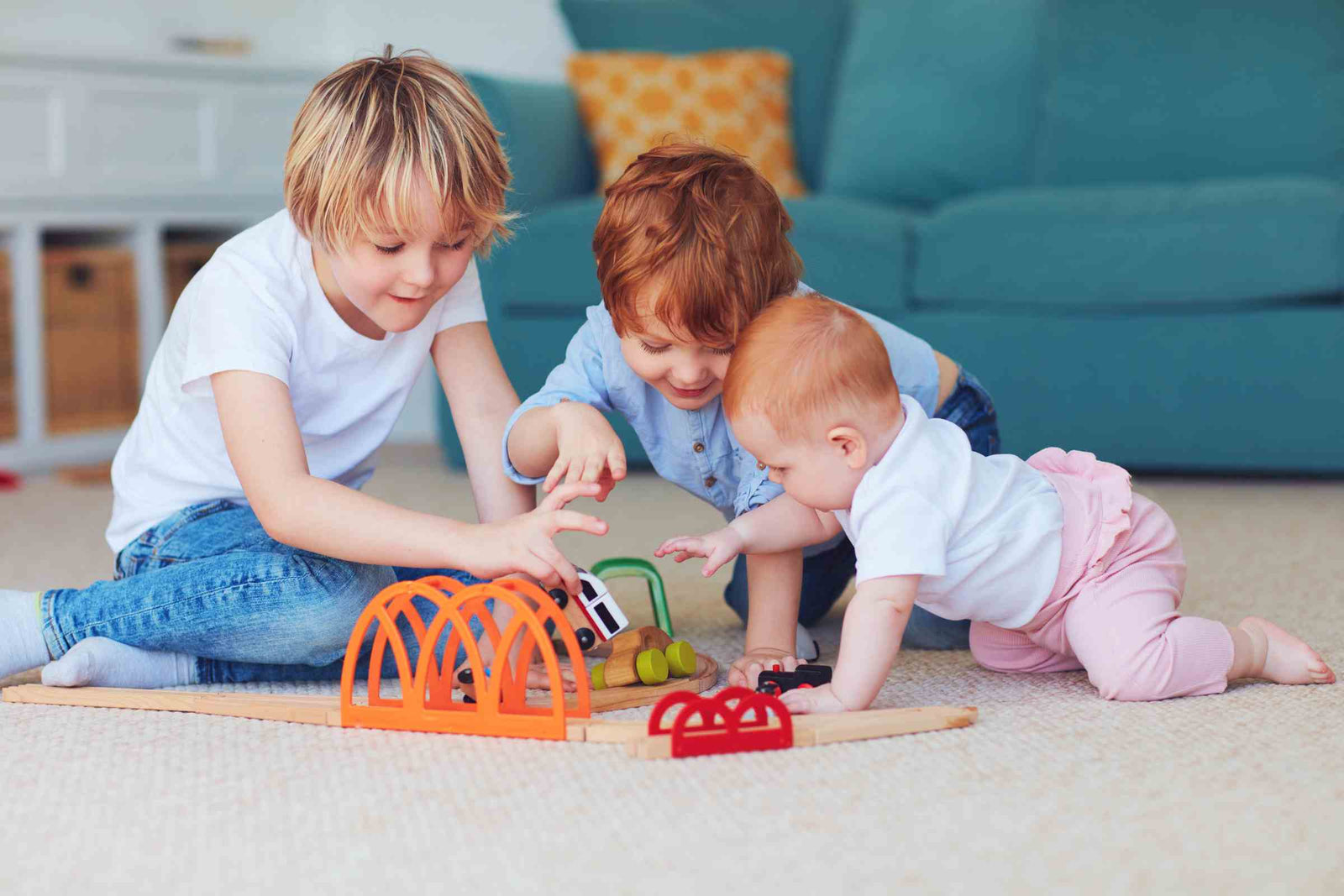 Three children including a baby playing with toys on the floor.