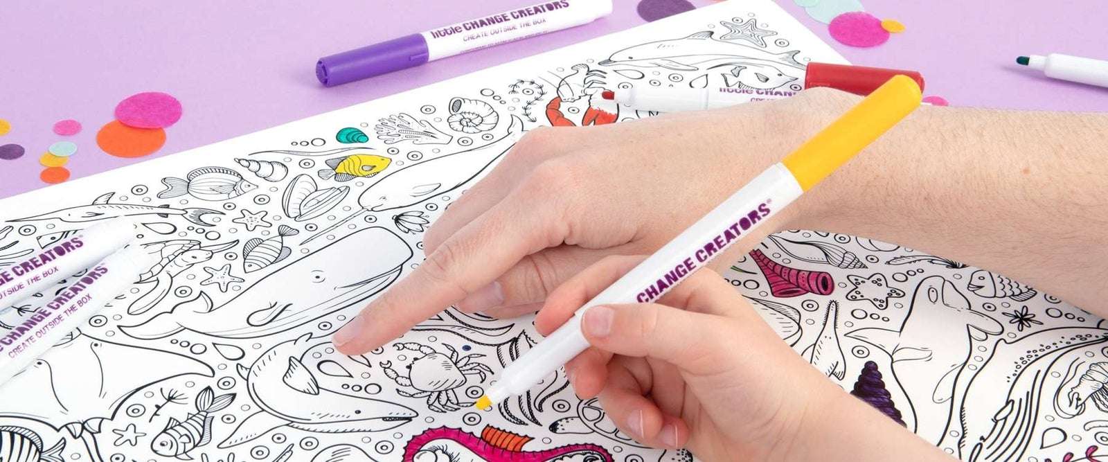 Adult pointing to image on silicone colouring mat with child holding yellow marker ready to colour