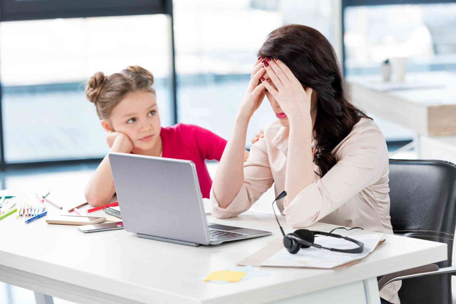 Frustrated Mum with head in hands on computer next to daughter