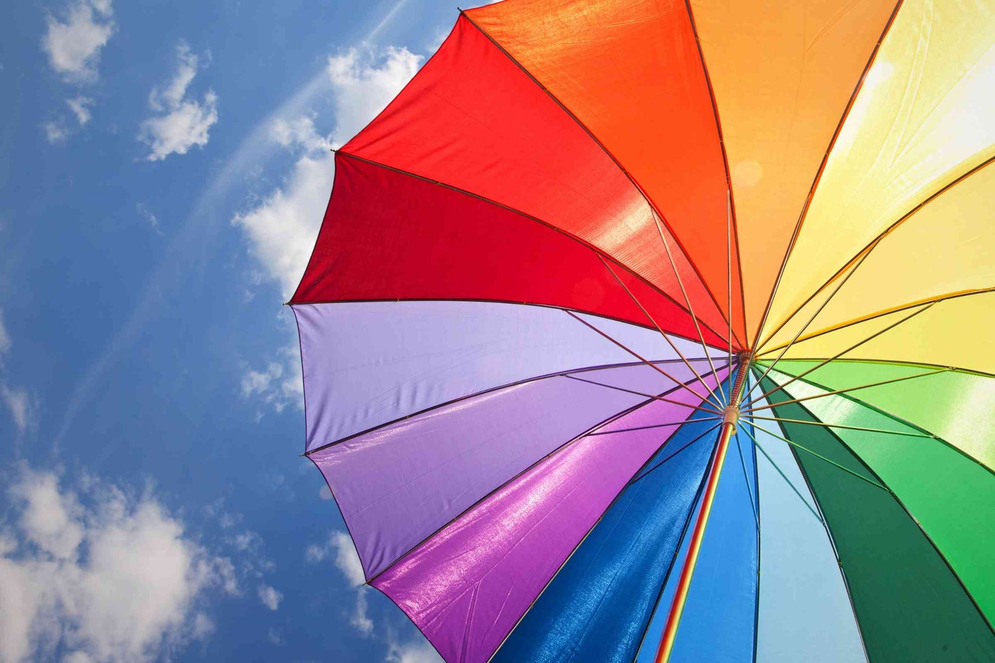 Rainbow umbrella with sunshine and sky in background