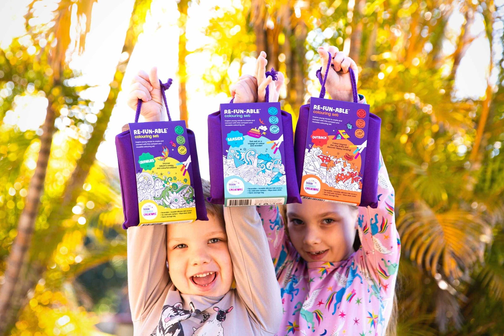 Two children holding Little Change Creators colouring sets