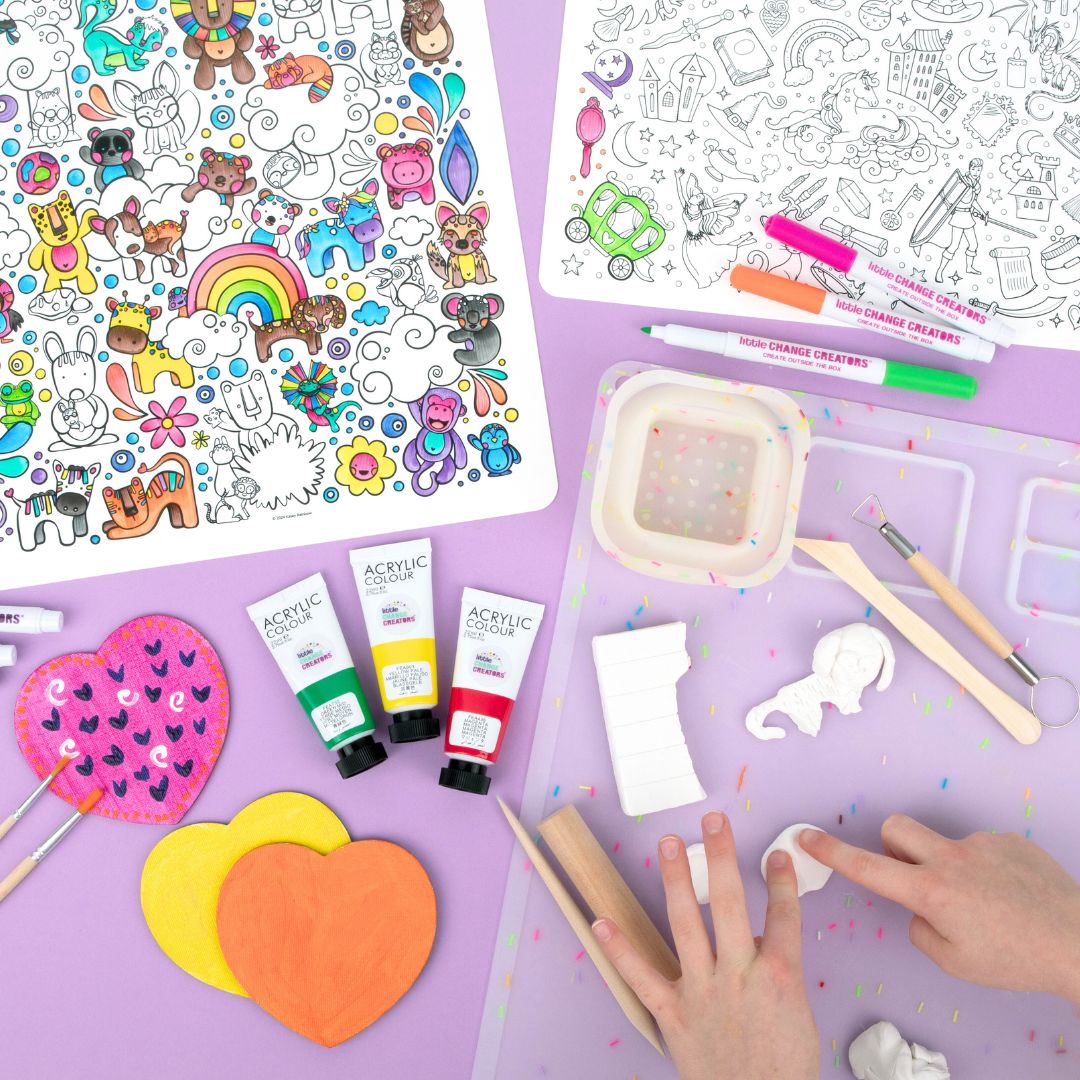 Reusable colouring sheets, acrylic paint tubes, and art supplies on a purple surface.