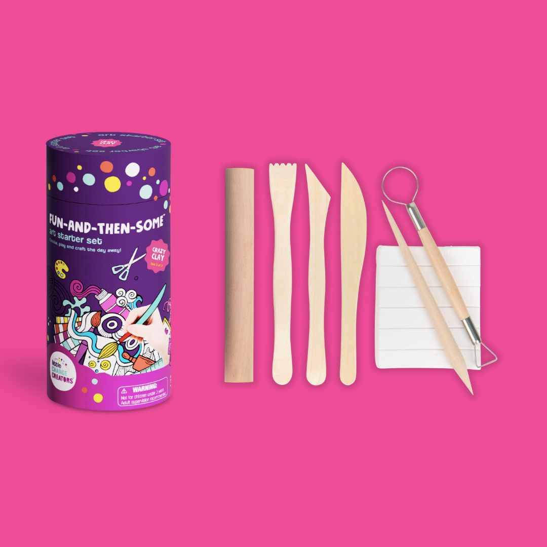 Kids clay modelling kit with gift packaging, wooden tools, and a block of clay on a pink background.
