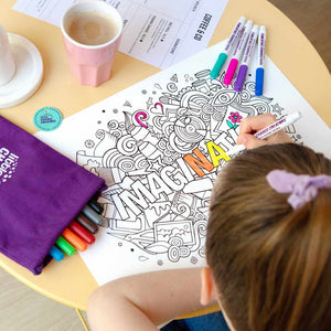 Young girl colouring Imagination reusable colour and draw mat on kids table with a drink