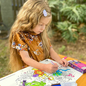 Young girl colouring a Safari reusable colouring mat in an outdoor garden setting