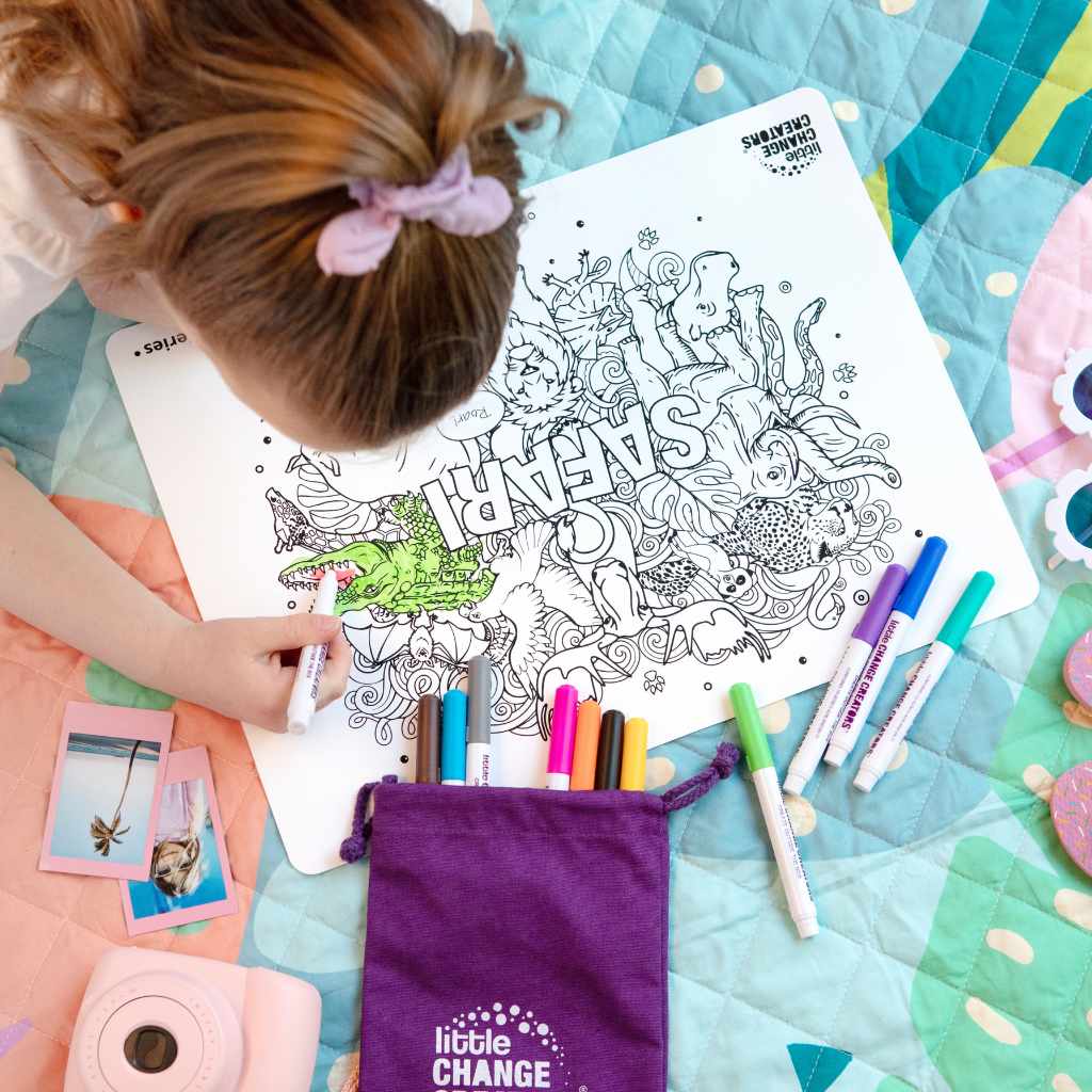 Young girl colouring in Safari reusable colouring mat on a rug with an instamatic camera beside her